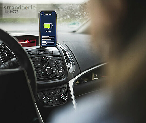 Frau mit Lade-App für Elektroautos auf dem Smartphone-Bildschirm