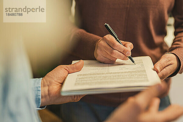 Hand einer reifen Frau füllt Formular mit Stift aus