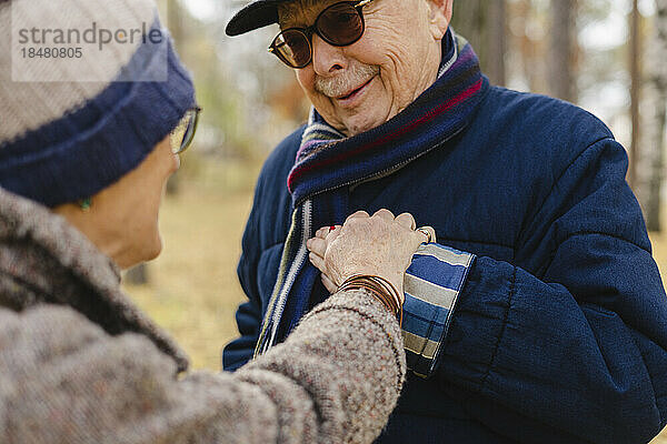 Ältere Frau hält Mann mit Sonnenbrille im Park an der Hand
