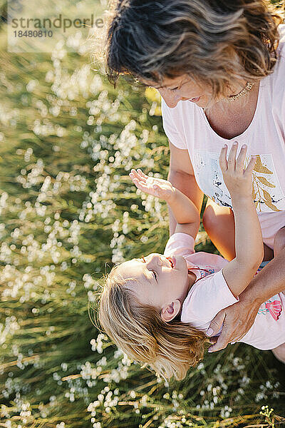Glückliches Mädchen mit verspielter Mutter im Sommerfeld