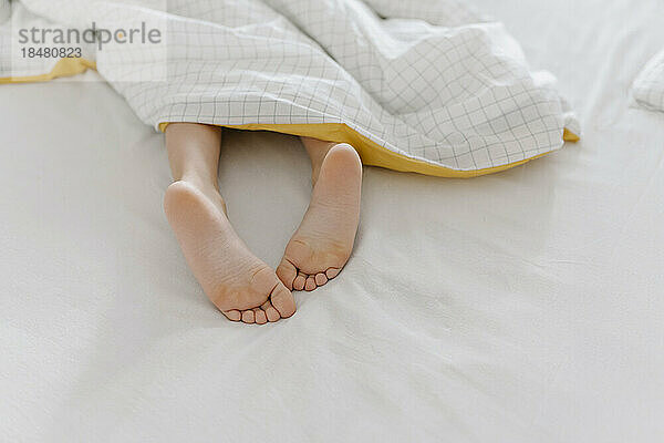 Girl with barefeet lying on bed at home