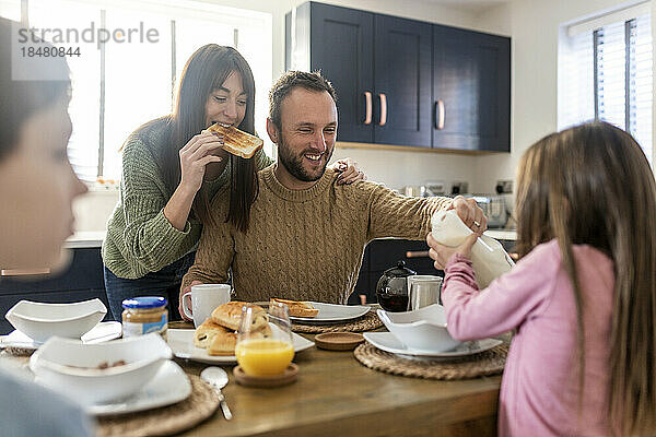 Glückliche Männer und Frauen frühstücken mit Kindern in der Küche