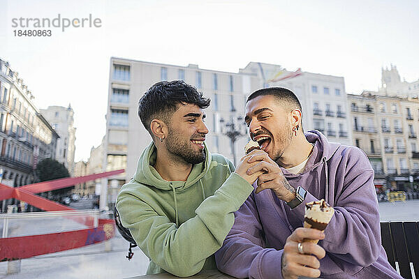 Glückliches schwules Paar  das Eis im Café im Freien isst