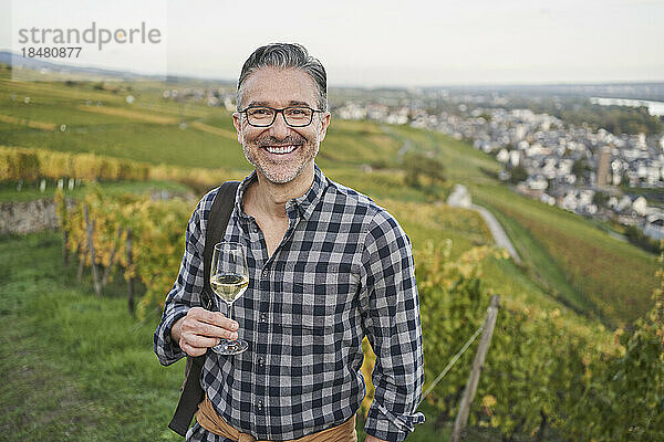 Glücklicher reifer Mann mit Weinglas auf Hügel
