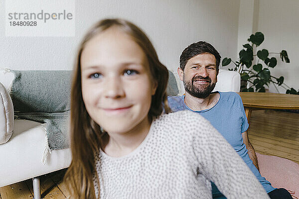 Glücklicher Mann blickt Tochter im Wohnzimmer an