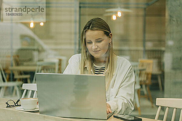 Blonde Geschäftsfrau benutzt Laptop im Café