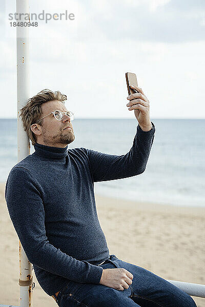 Mann benutzt Mobiltelefon am Strand