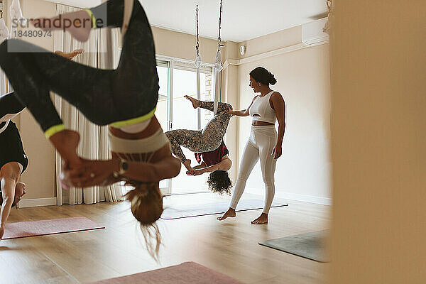 Lehrer  der Schülern im Studio Aerial Yoga beibringt