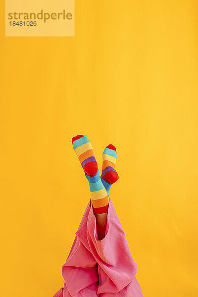 Woman wearing colorful socks against yellow background