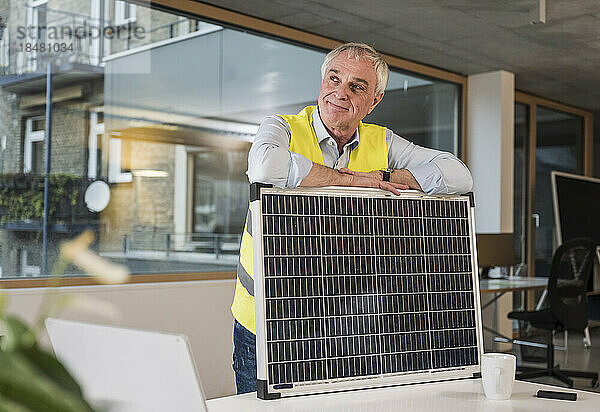 Nachdenklicher leitender Ingenieur mit Solarpanel im Büro