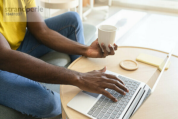 Freiberufler mit Kaffeetasse  der zu Hause am Laptop arbeitet