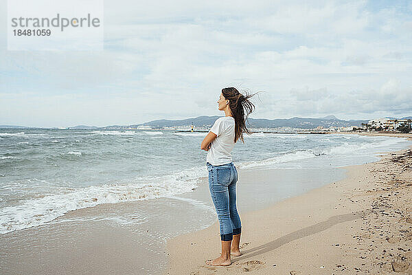 Frau steht auf Sand in Ufernähe am Strand