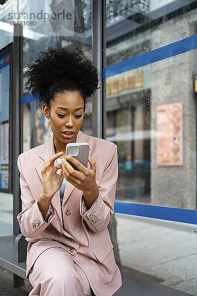 Geschäftsfrau benutzt Smartphone auf Bank sitzend