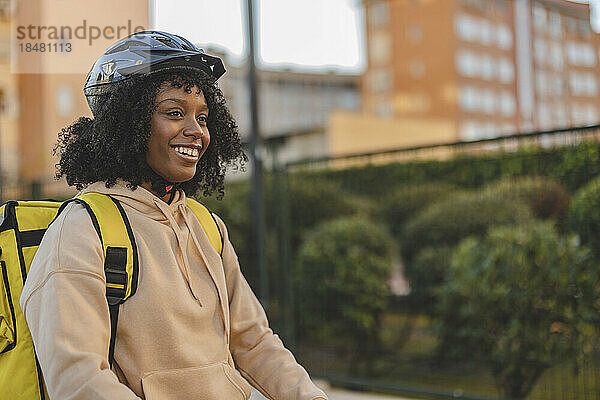 Glückliche Lieferfrau mit Helm und Rucksack