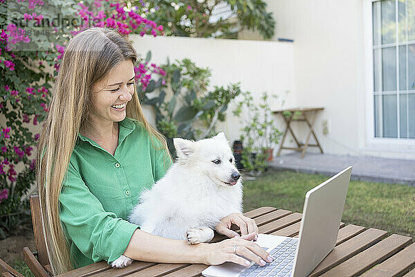 Freiberufler mit Hund nutzt Laptop im Garten