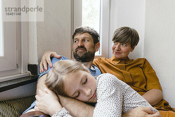 Father and mother with daughter relaxing at home