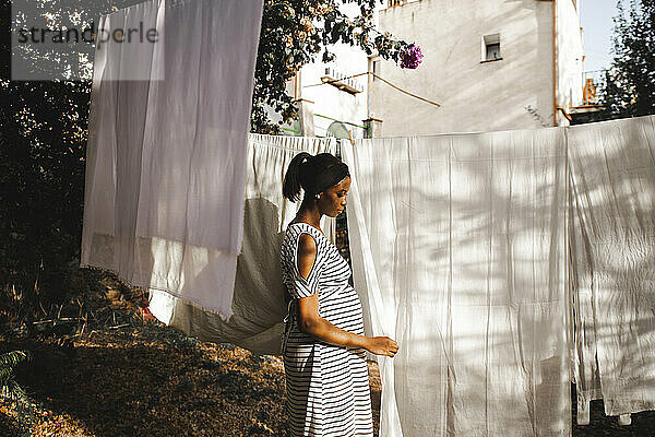 Pregnant woman hanging white sheet in backyard