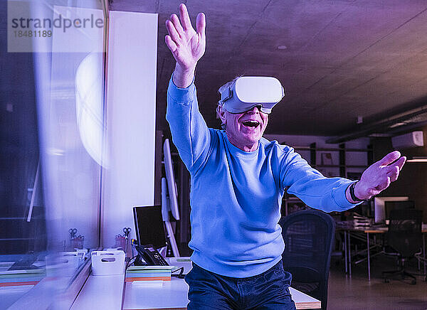 Fröhlicher Geschäftsmann mit Virtual-Reality-Headset im Büro