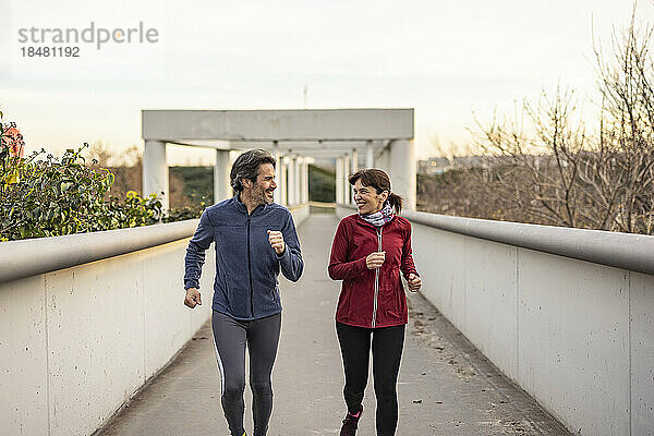 Glückliches älteres Paar joggt auf der Brücke