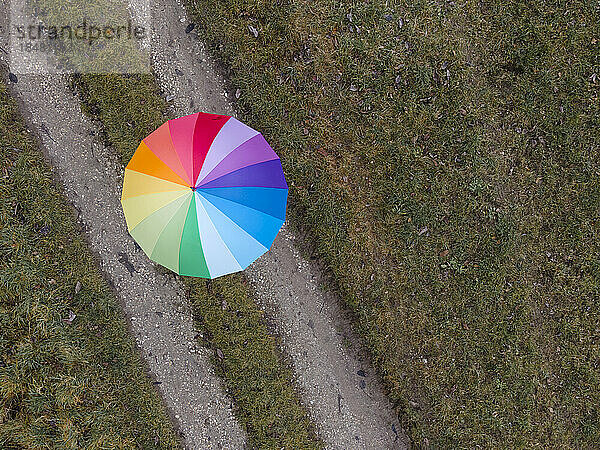Woman with multi colored umbrella on footpath