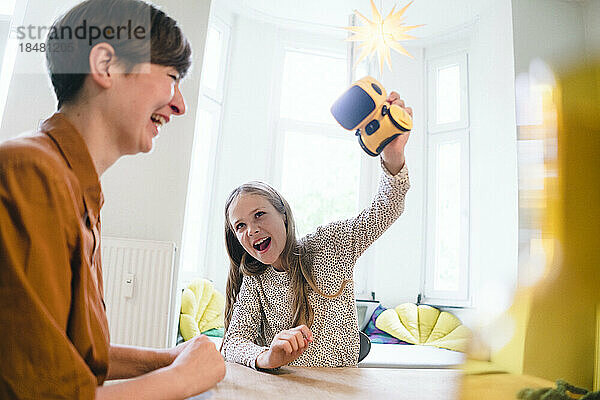 Playful daughter holding robot by mother at home