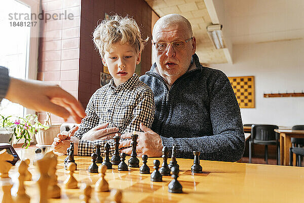 Großvater und Enkel spielen Schach im Sportverein