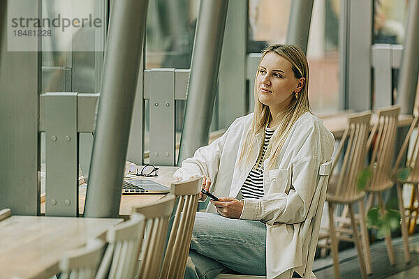 Nachdenkliche Geschäftsfrau sitzt auf einem Stuhl im Café