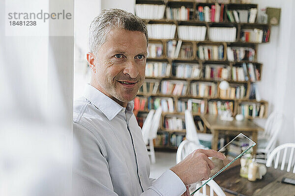 Lächelnder Geschäftsmann mit futuristischem transparentem Tablet-PC
