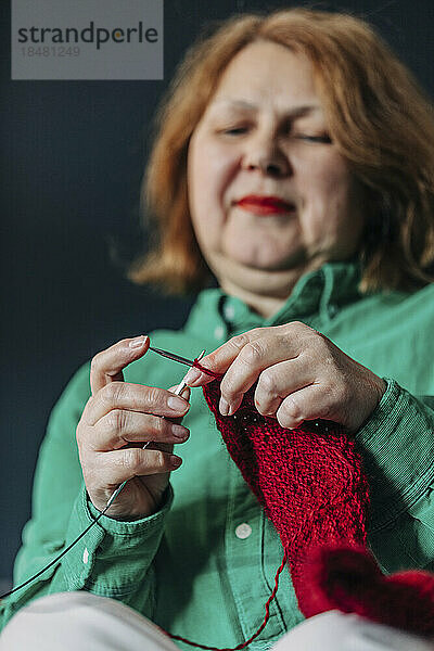 Ältere Frau strickt roten Pullover