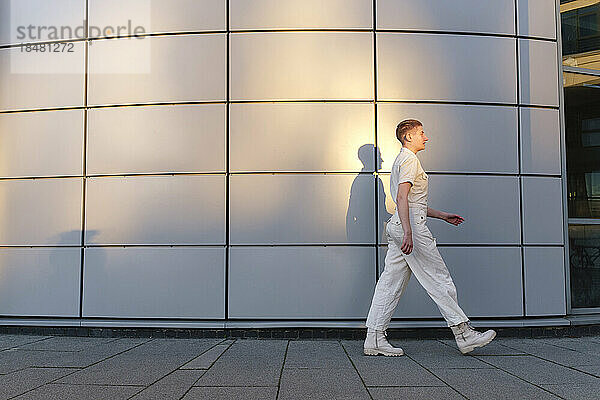 Non-binary person walking in front of building