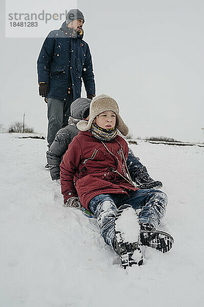 Vater und verspielter Sohn sitzen im Schnee