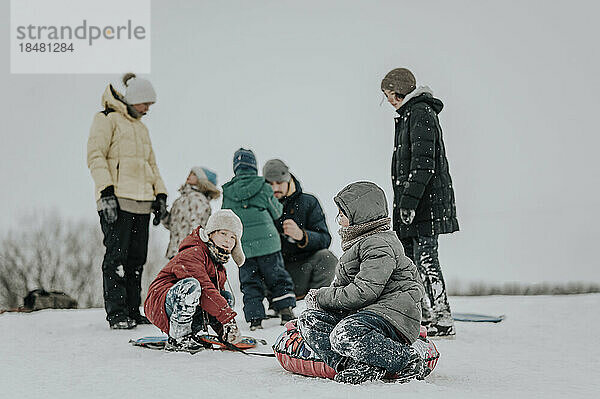 Glückliche Familie  die zusammen Spaß mit aufblasbarem Schlitten im Schnee hat