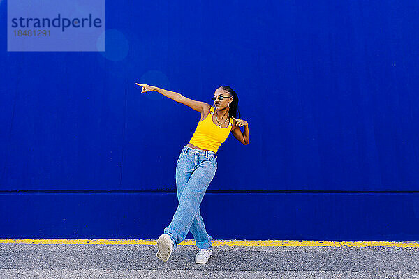 Junge Frau tanzt vor blauer Wand