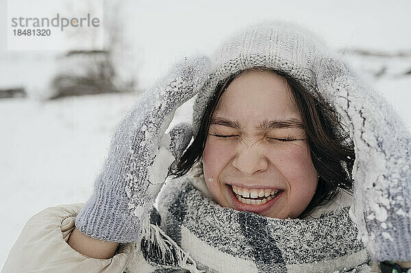 Fröhliches Teenager-Mädchen mit Strickmütze genießt den Winter
