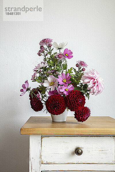 Bouquet of red and pink autumn flowers on night table