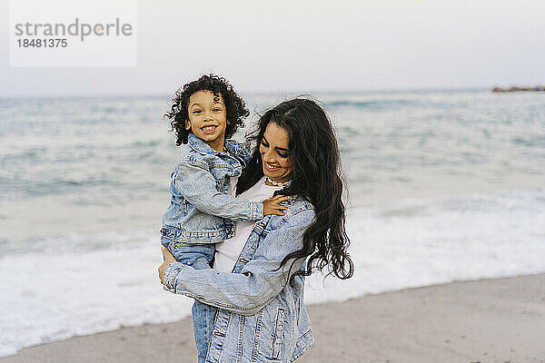 Mutter und Sohn tragen Jeansjacken am Strand