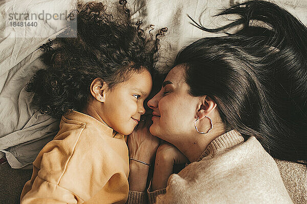 Lächelnde Mutter mit Tochter  die zu Hause im Bett liegt