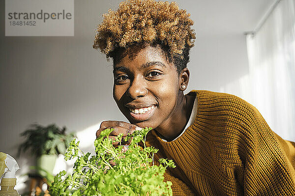 Lächelnde junge Frau mit Pflanze zu Hause