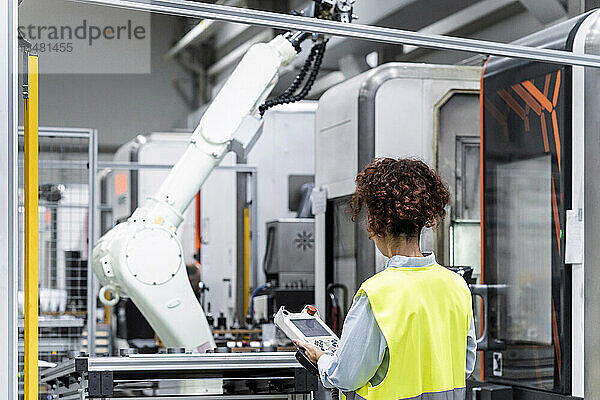 Ingenieur steuert Roboterarm mit Ausrüstung in der Fabrik