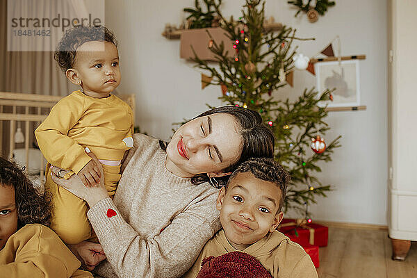 Lächelnde Mutter mit Sohn und Töchtern  die sich zu Weihnachten amüsieren