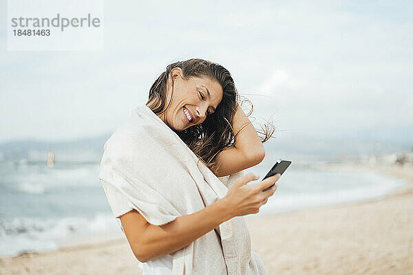 Glückliche Frau benutzt Smartphone am Strand