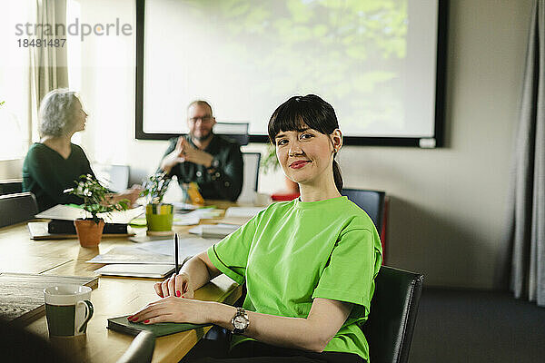 Porträt einer Frau im grünen T-Shirt während einer Besprechung im Konferenzraum