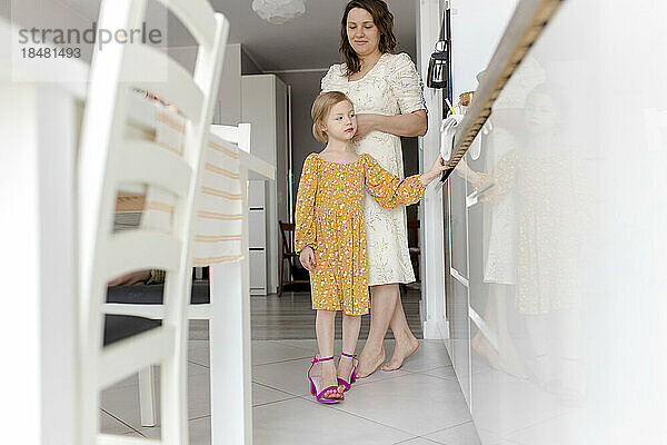 Mädchen trägt Mutters Schuhe in der heimischen Küche