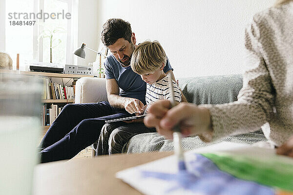 Vater erklärt Sohn  der zu Hause mit Tablet-PC sitzt