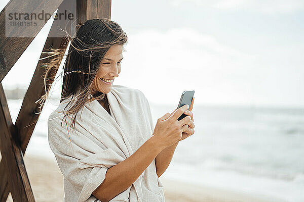 Glückliche Frau benutzt Smartphone am Strand