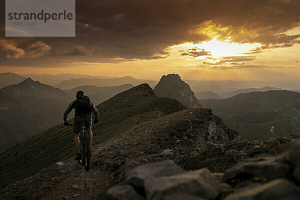Mann radelt bei Sonnenuntergang auf dem Berg