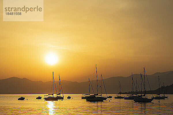 Italien  Venetien  Bardolino  Silhouetten von Segelbooten  die bei Sonnenuntergang im Gardasee schwimmen