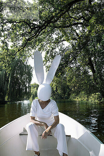 Woman wearing white rabbit mask sitting in boat