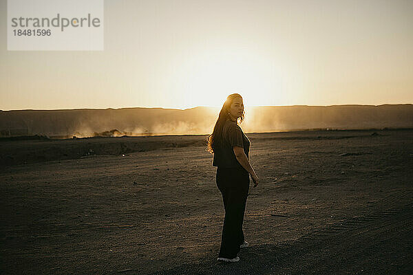 Junge Frau läuft bei Sonnenuntergang auf einer unbefestigten Straße