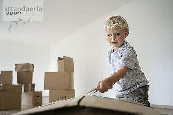 Boy opening cardboard box at new home